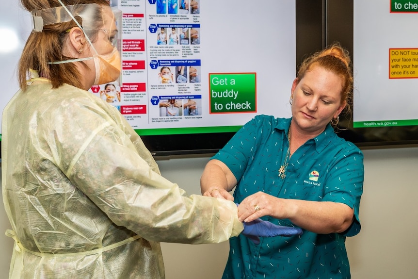 A carer wearing PPE is helped by colleague, Jade Murray