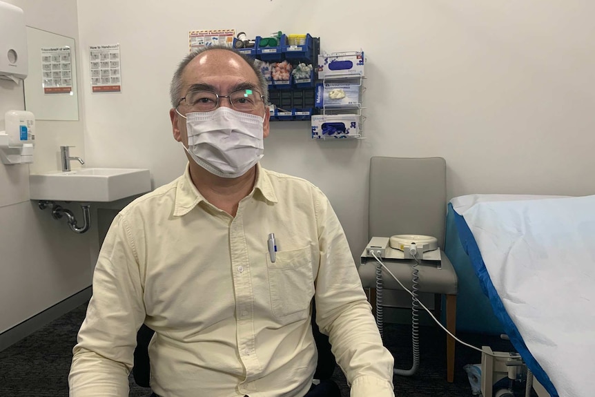 a man with a surgical mask sitting in a medical clinic