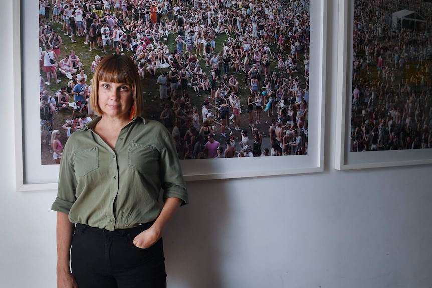 Adelle Robinson Director of Fuzzy music standing in front a festival picture hanging on a wall inside her Sydney office.