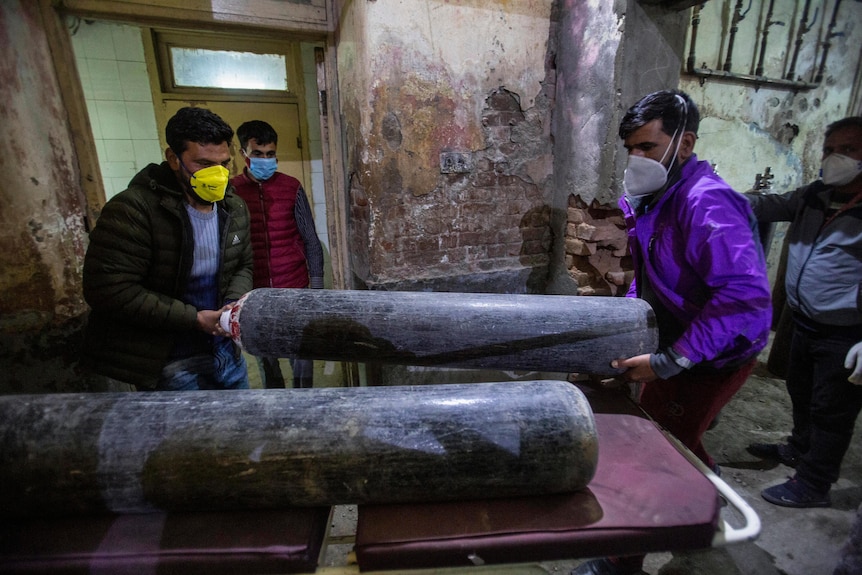 Several men carry a large oxygen cannister