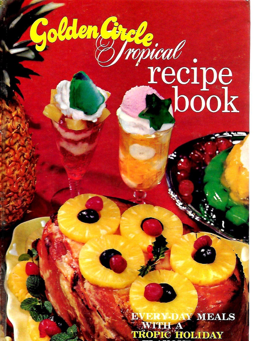 Cover of Golden Circle Tropical Cookbook, with a circle of pineapples and two cocktail glasses against a red background.