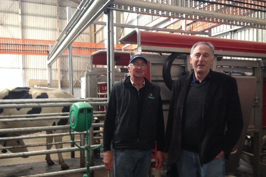 Two men, Garry Carpenter and Garth Whitehead, standing in a shed in front of a robotic dairy in operation in north-west Tasmania
