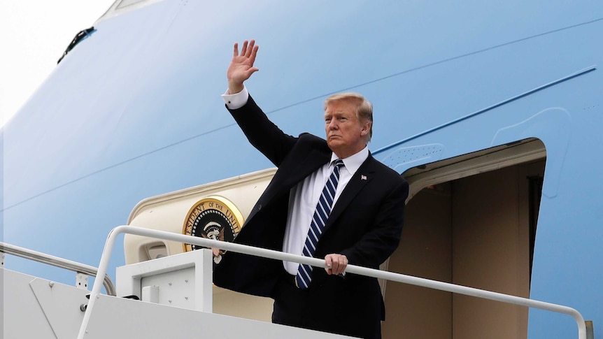 US President Donald Trump raises his right hand to wave as he boards Air Force One plane.