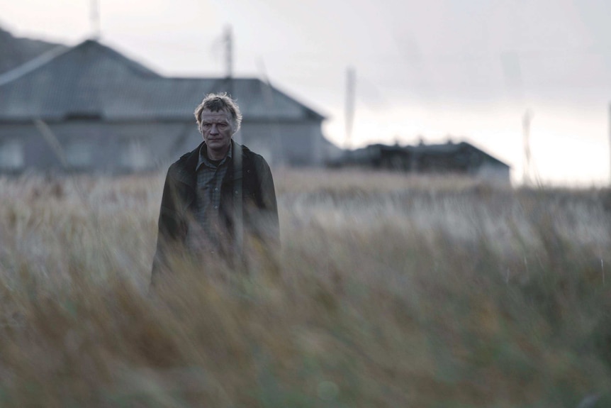 An older man in a dry field in the film Leviathan