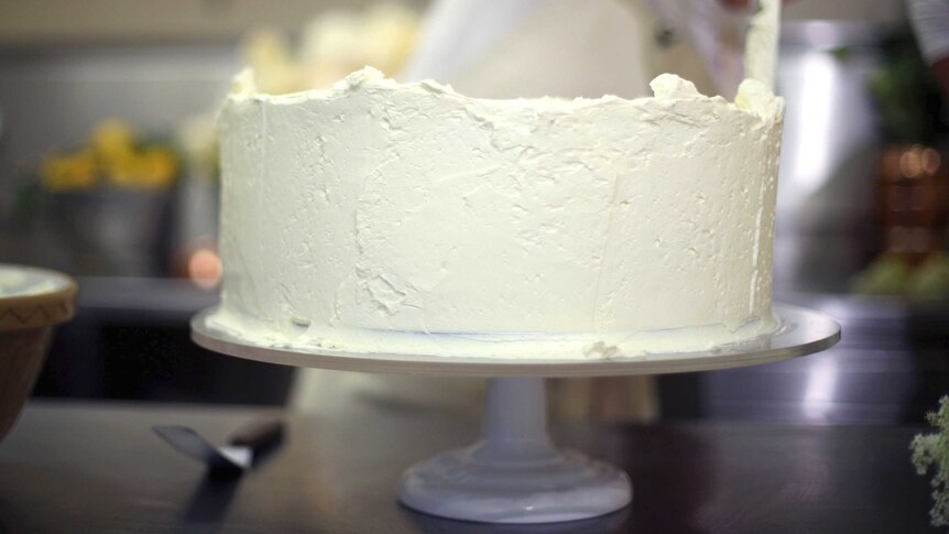 A baker ices a cake.