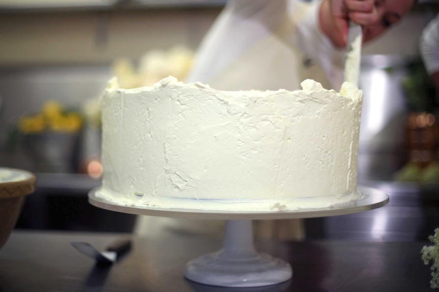 A baker ices a cake.