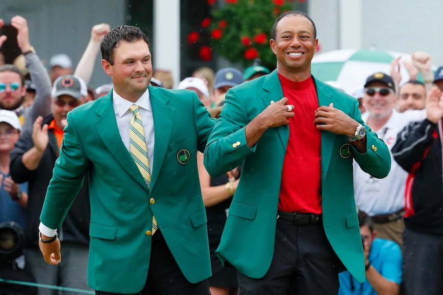 Patrick Reed places the green jacket on Tiger Woods at the 2019 Masters tournament.