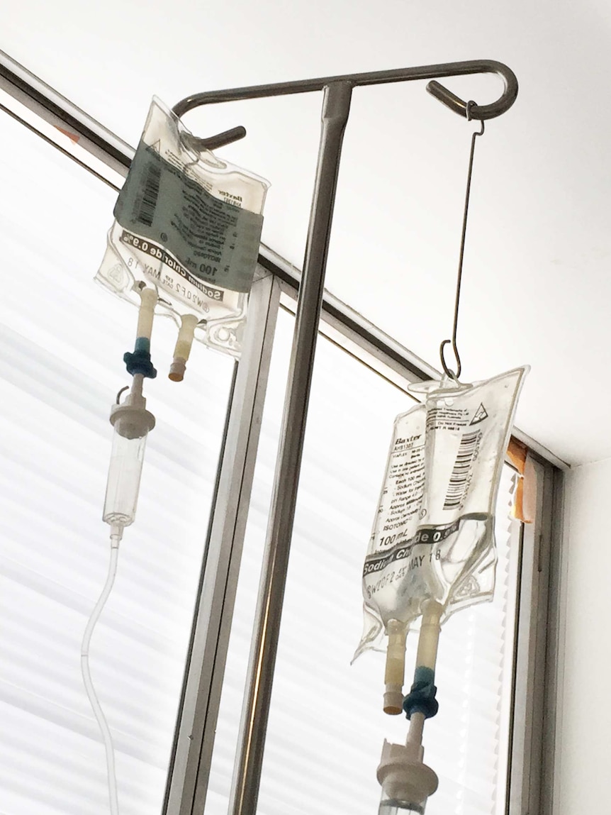 Intravenous drips hanging from a stand in hospital ward.