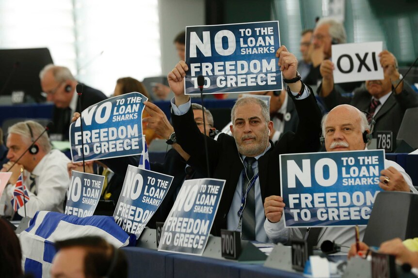 Members of the European parliament hold placards reading "No to the loan sharks - freedom to Greece".