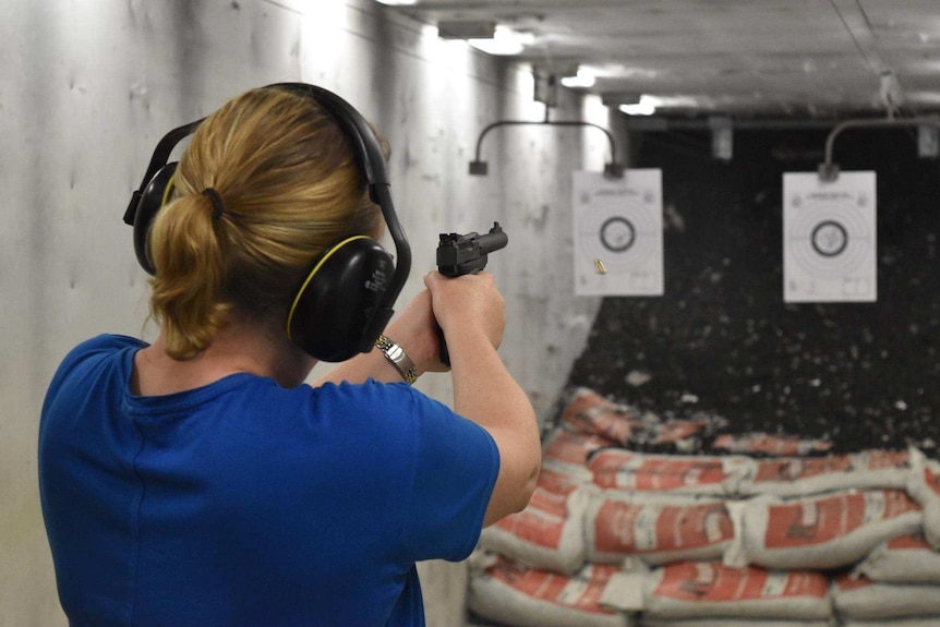 Back of woman shooting at indoor shooting range
