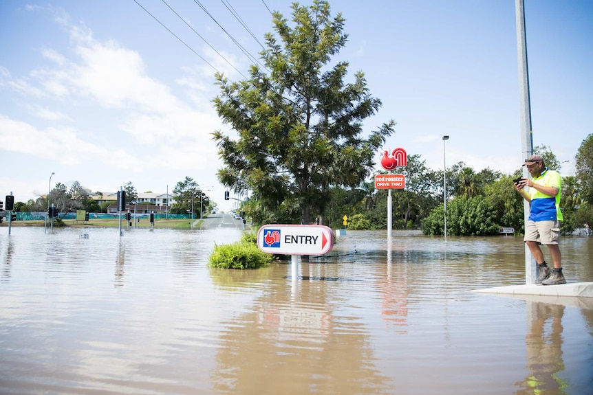 Red Rooster sign is visible as flood waters rise in Beenleigh.