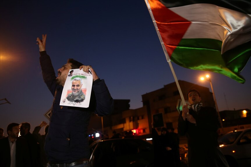 A man holds a picture of late Iranian Major-General Qassem Soleimani.