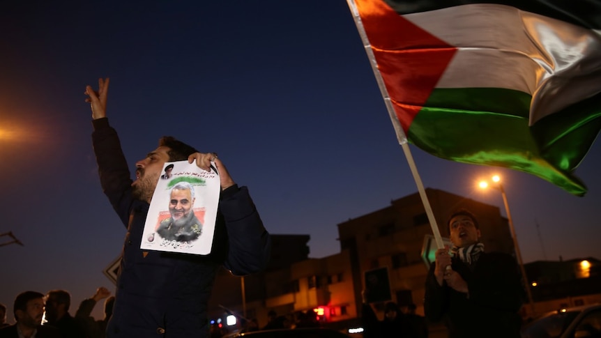A man holds a picture of late Iranian Major-General Qassem Soleimani.