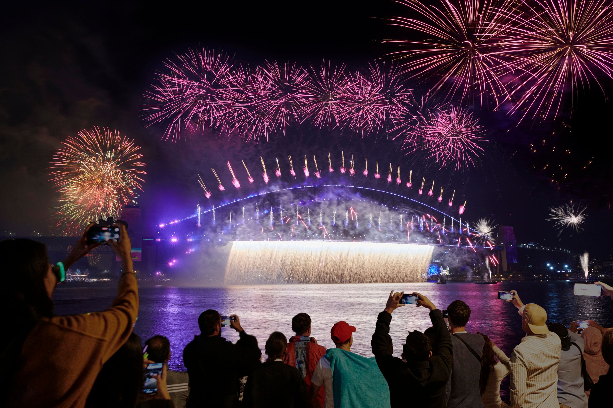 The Sydney Harbour Bridge on NYE with fireworks and spectators watching