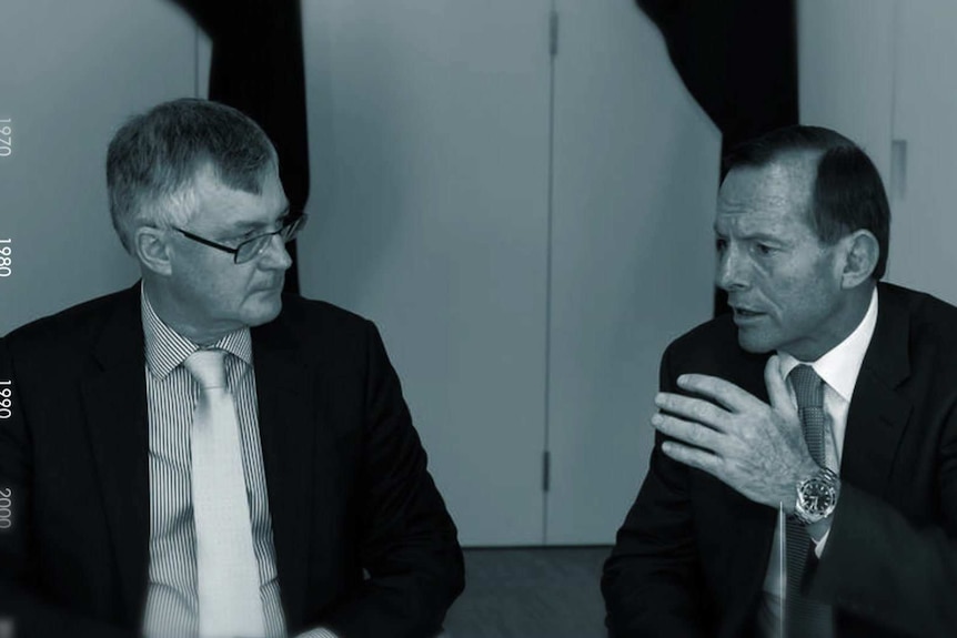 Martin Parkinson and Tony Abbott talk. Mr Abbott is gesturing with his hand.