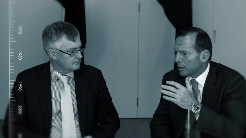 Martin Parkinson and Tony Abbott talk. Mr Abbott is gesturing with his hand.