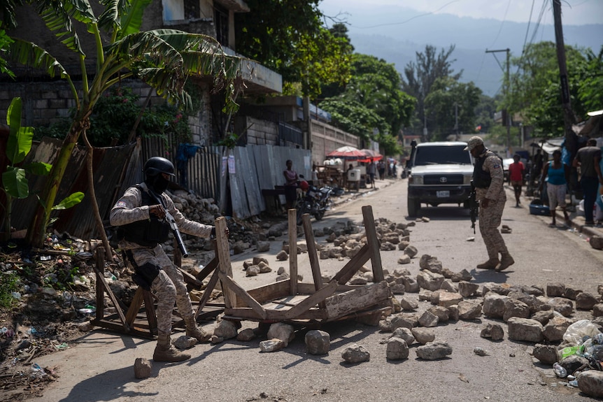 Police removing a makeshift roadblock of rocks and a table