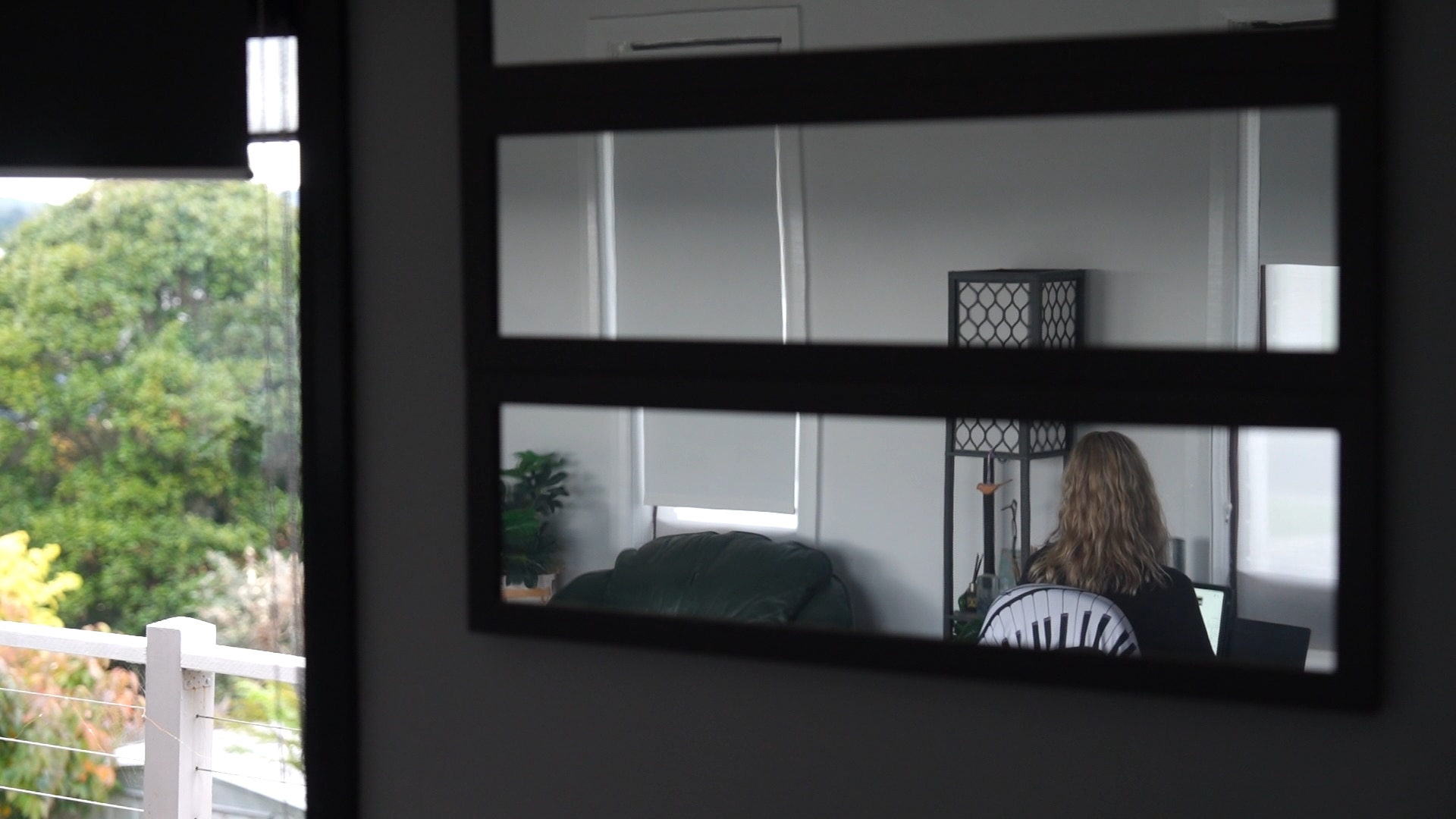 A mirror shows a woman playing the piano