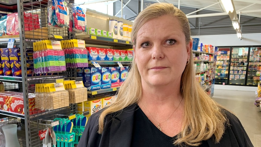 A woman with blonde hair stands in front of a supermarket shelf