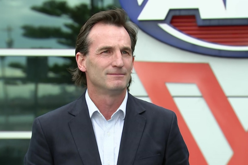 A man stands in front of a large AFL sign in Melbourne.