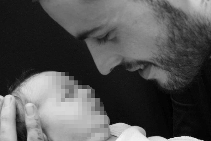 A black and white picture of Mitchell Finnerty cradling his baby son Cruz.