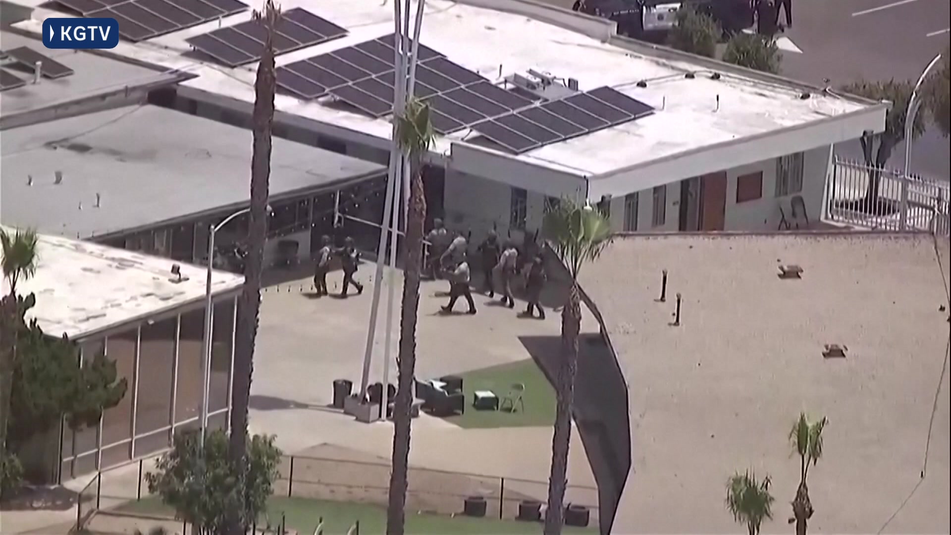 An aerial view of armed police approaching a building