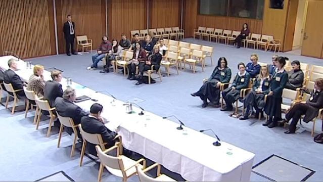 Student stands to address people sitting on committee panel