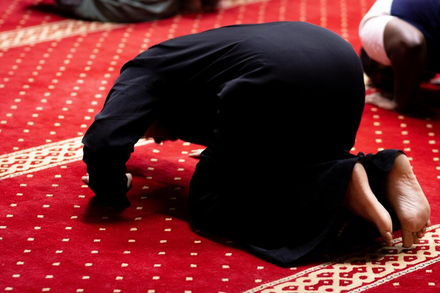 A man on his knees on red carpet during prayer at the Darwin Mosque.