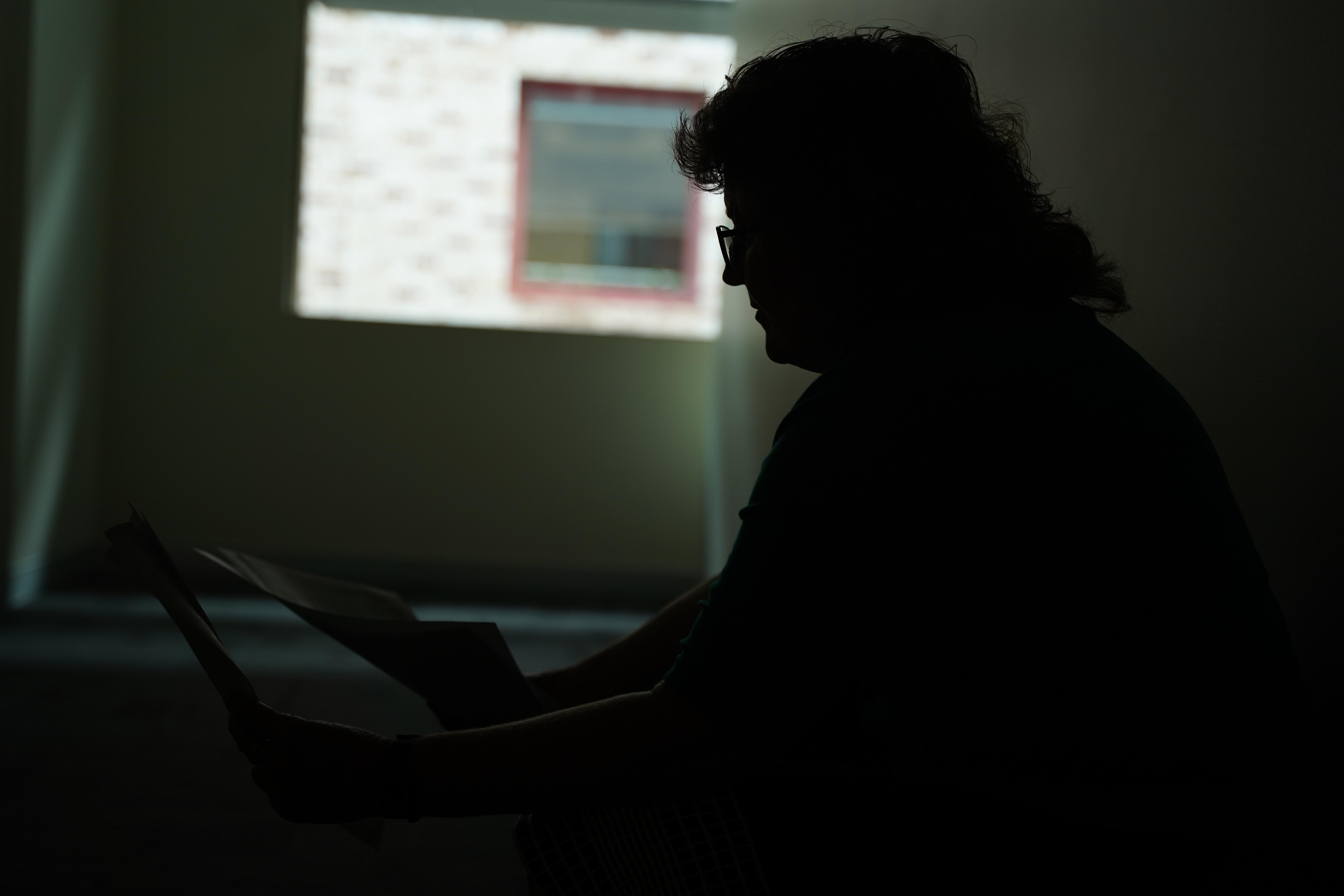 A woman sitting down staring at a paper.