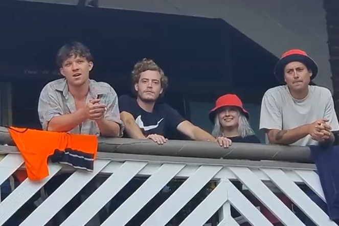 four young people on a balcony looking down