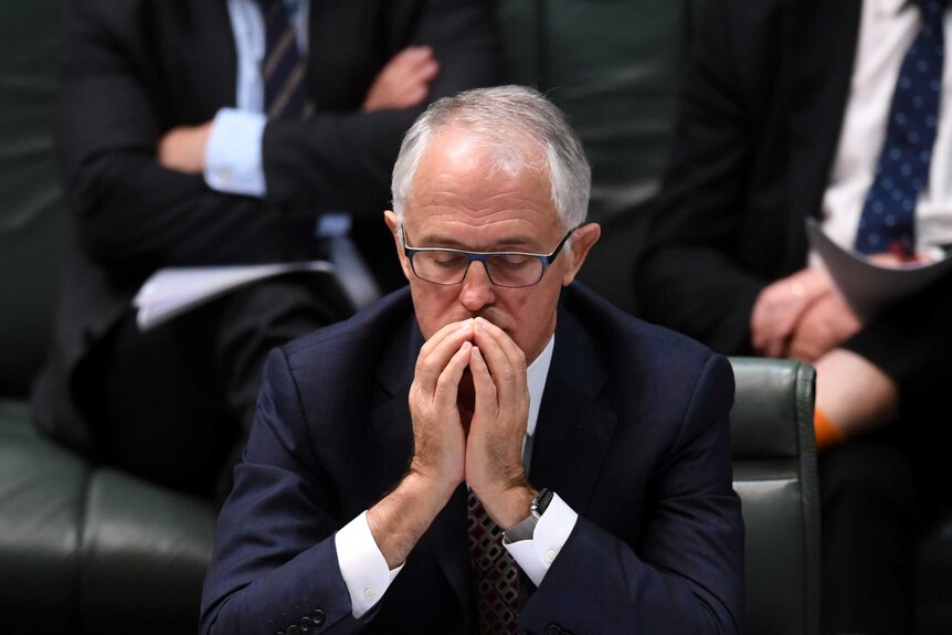 Malcolm Turnbull sits with his hands poised in front of his face, eyes closed.