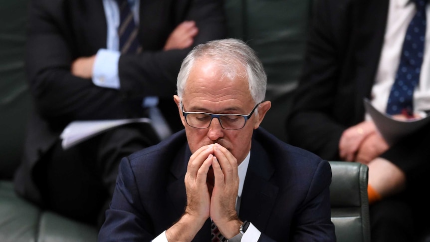 Malcolm Turnbull sits with his hands poised in front of his face, eyes closed.