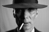 A black-and-white close-up of a gaunt and harrowed-looking man with a stetson hat and a cigarette in his mouth.