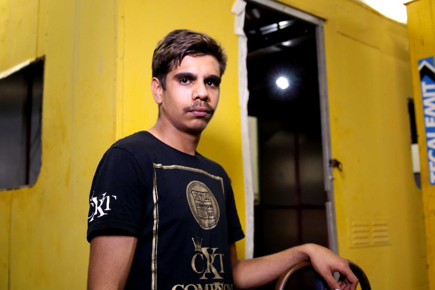 A teenage boy standing in an industrial-style room.