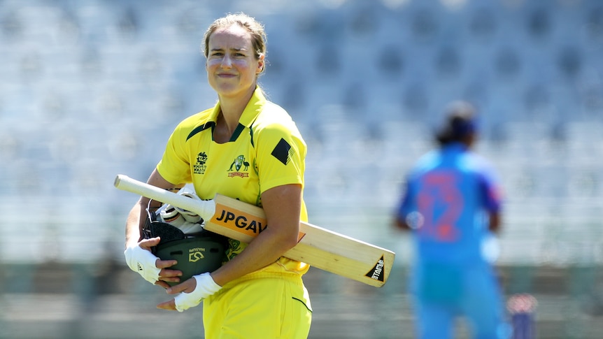 Australia batter Ellyse Perry winces as she walks off with her helmet and bat in her hands after getting out against India.