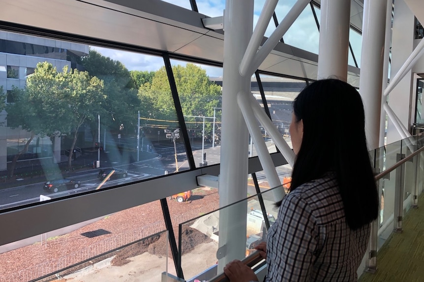 Betty looks out onto the streets from inside a building with glass windows.