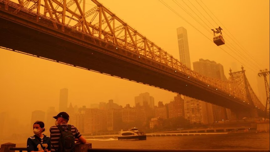 People standing under a bridge with orange haze around them