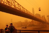 People standing under a bridge with orange haze around them