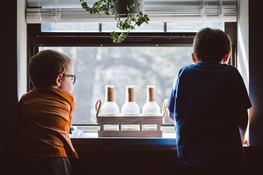 Two boys look out a window for a story on leaving children at home alone