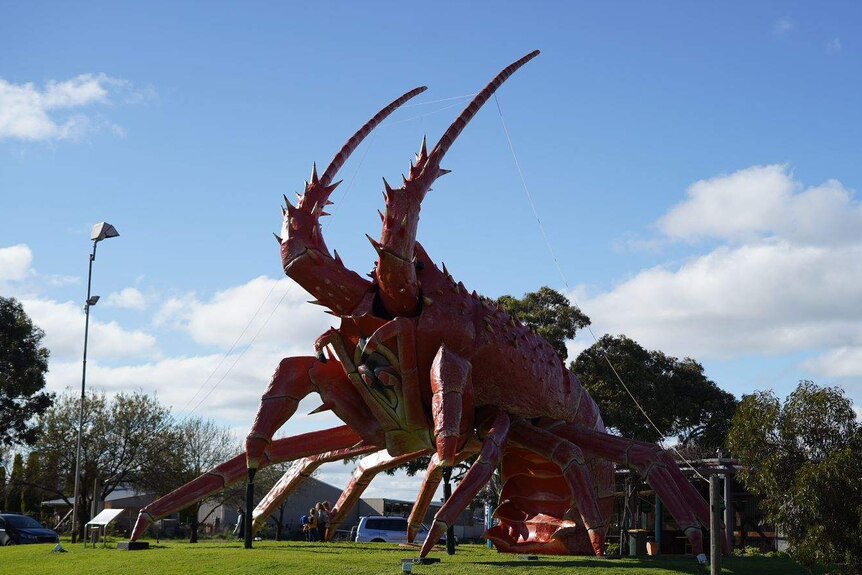 A giant red lobster sculpture stands proudly against a blue sky