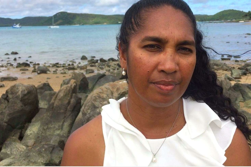 A woman standing on a coastline with boast in the background