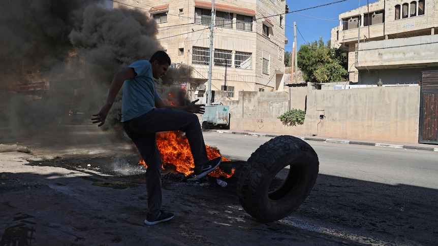 Palestinian demonstrator burns tires in clash with Israeli soldiers