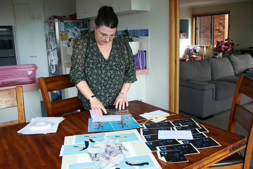 A woman with dark hair looks at pictures on a table