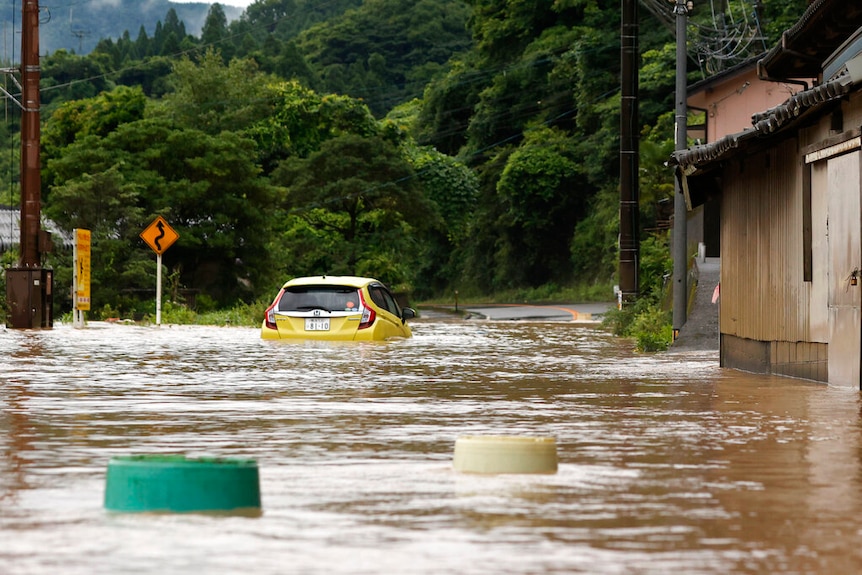 A car is stuck in a flooded road by heavy rain in Yatsushiro, Kumamoto prefecture, southwestern Japan, Saturday.