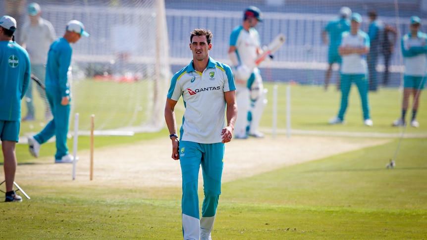 A man in cricket clothes walking away from a pitch 