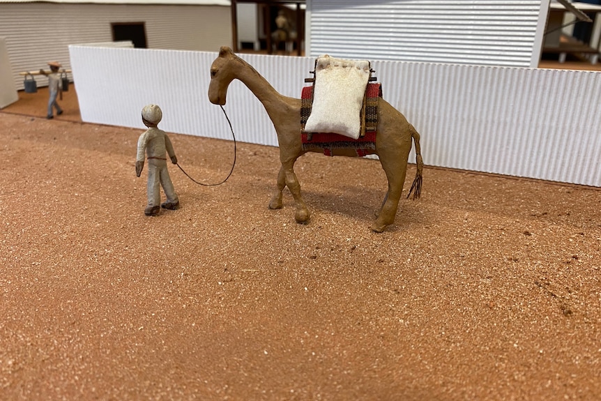 A miniature figurine of a camel and a man leading it