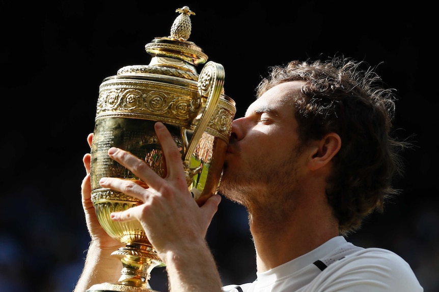Andy Murray kisses the Wimbledon trophy.