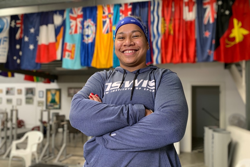 Woman with blue headband and grey top smiles at camera.