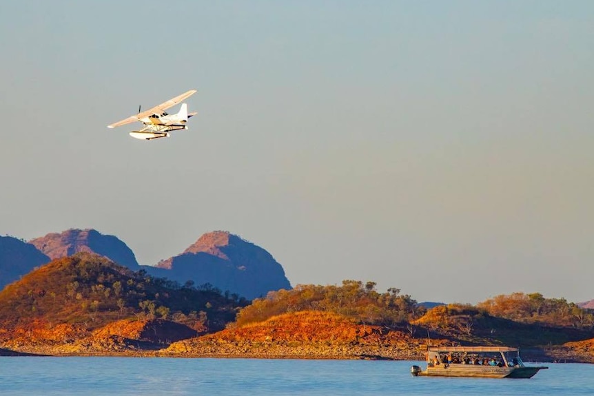 Image of a seaplane taking off near a house boat on Lake Argyle.