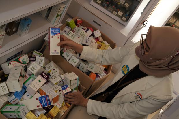 A pharmacist looking at a drawer full of medicines.